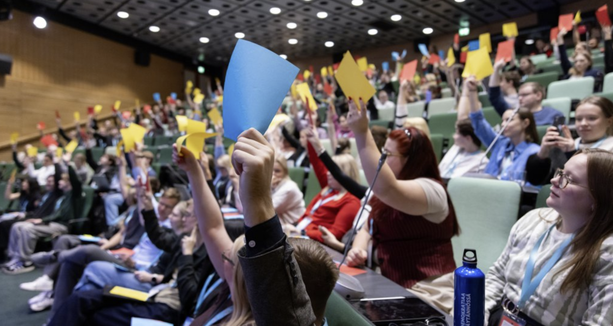 Unga som röstar med färggranna papperslappar i ett auditorium