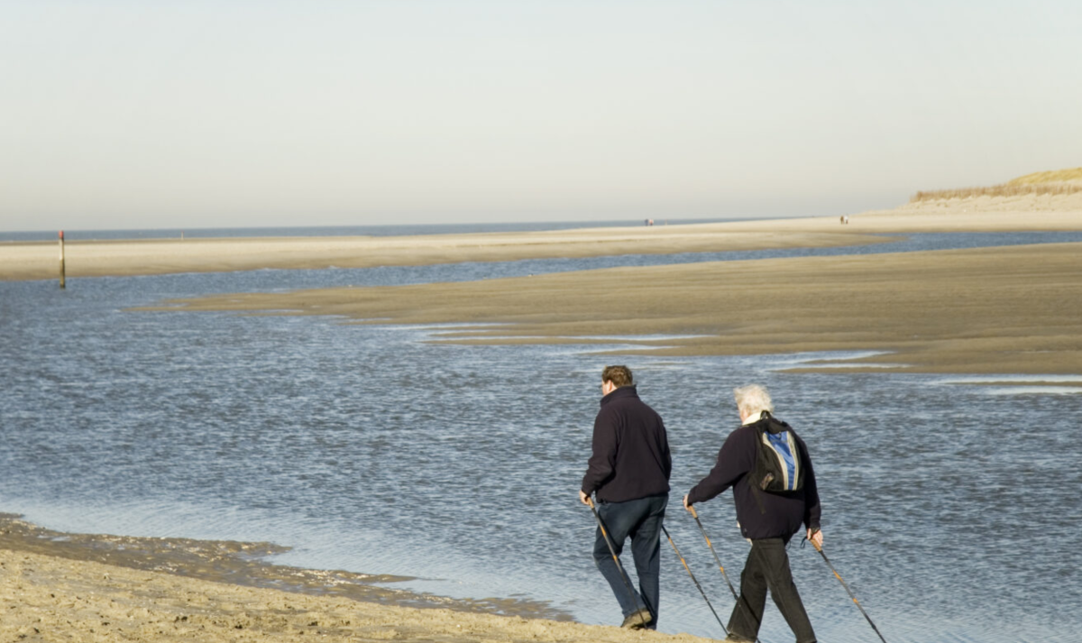 Two older adults taking a walk on the beach