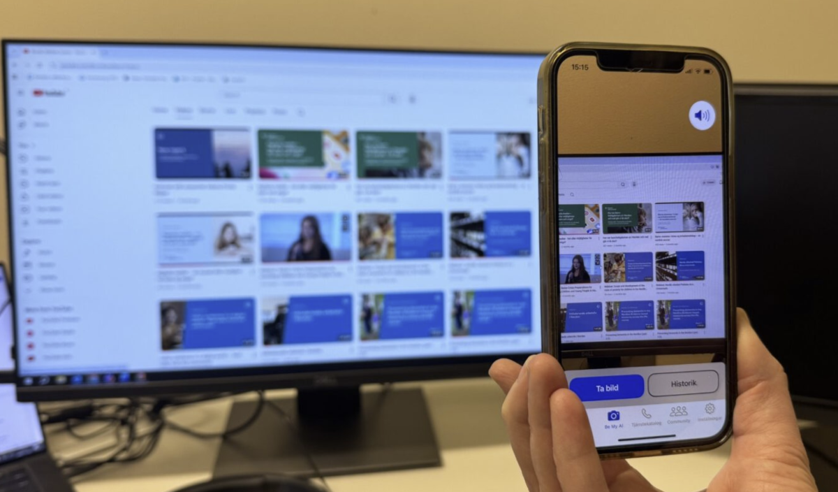 A hand holding a phone taking a picture of a computer screen.