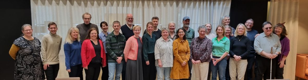 Gruppebilde av 25 personer som står på rad og ser mot kameraet.