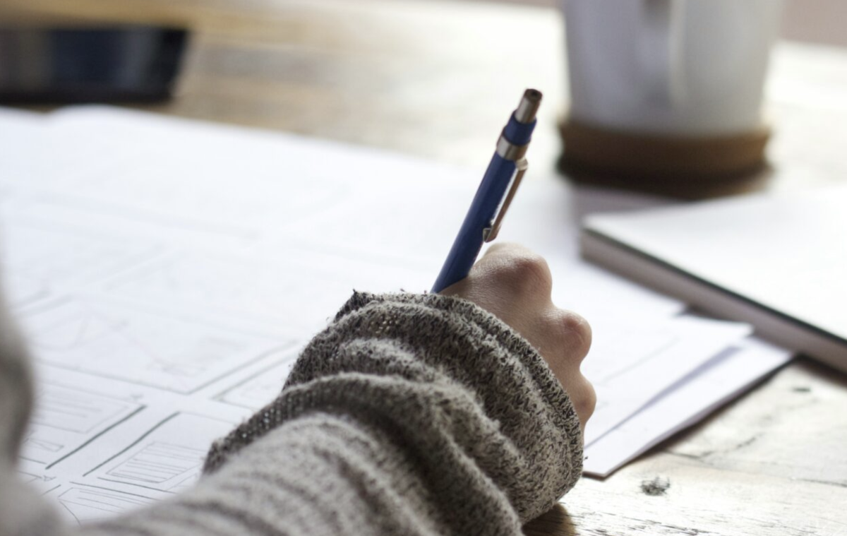 A hand holding a pen and writing