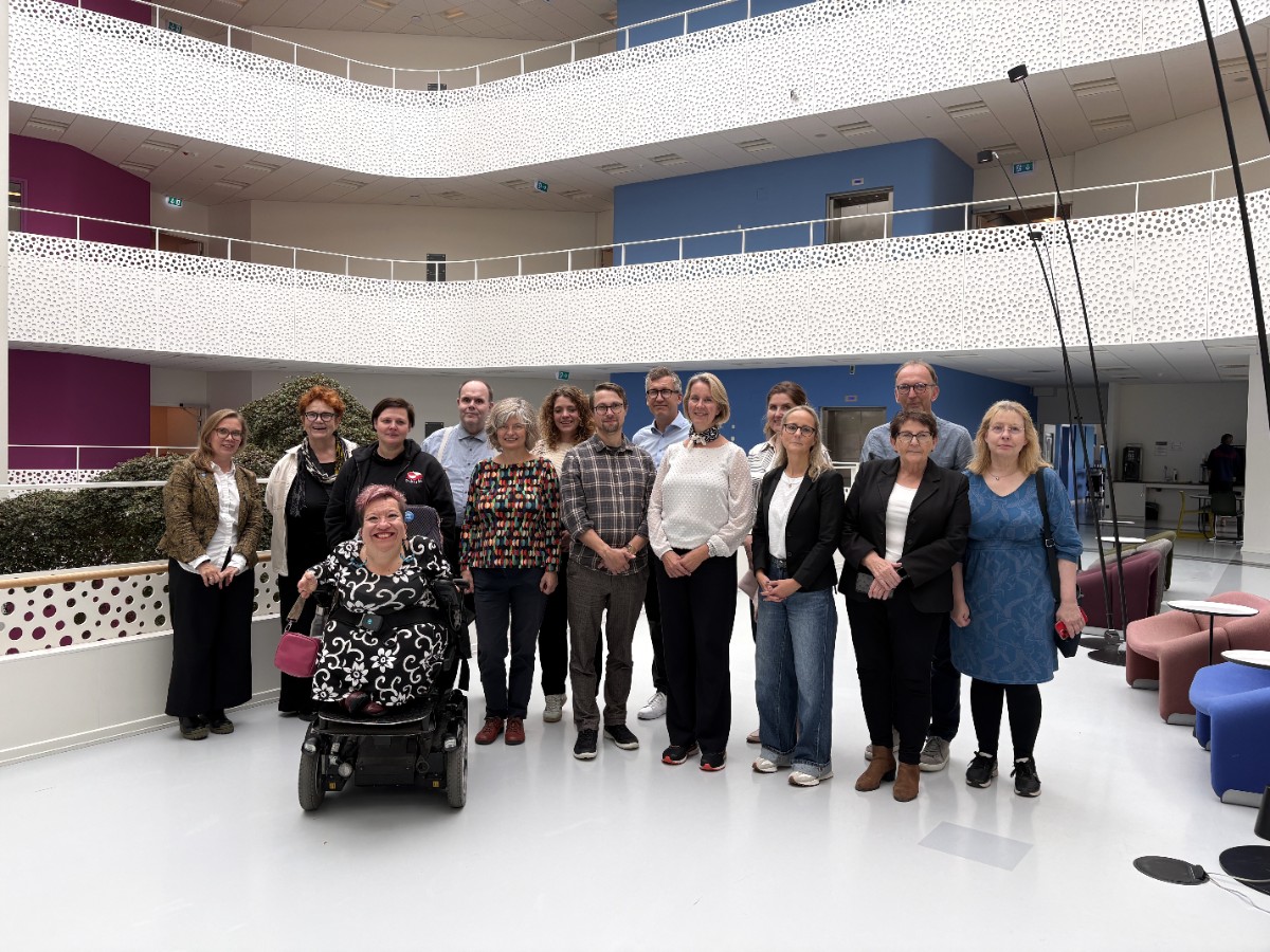 Gruppbild med 15 personer i ett öppet, ljust utrymme