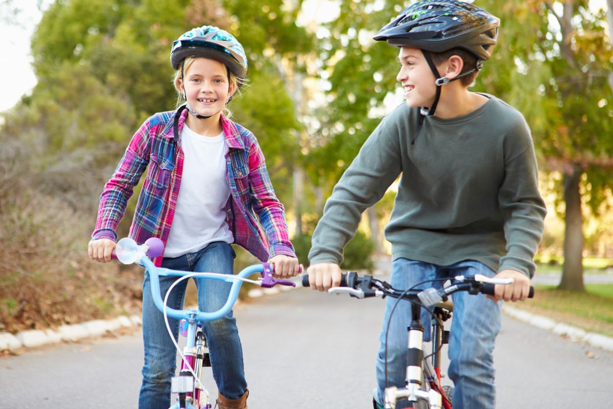 En glad flicka och pojke cyklar på varsin cykel