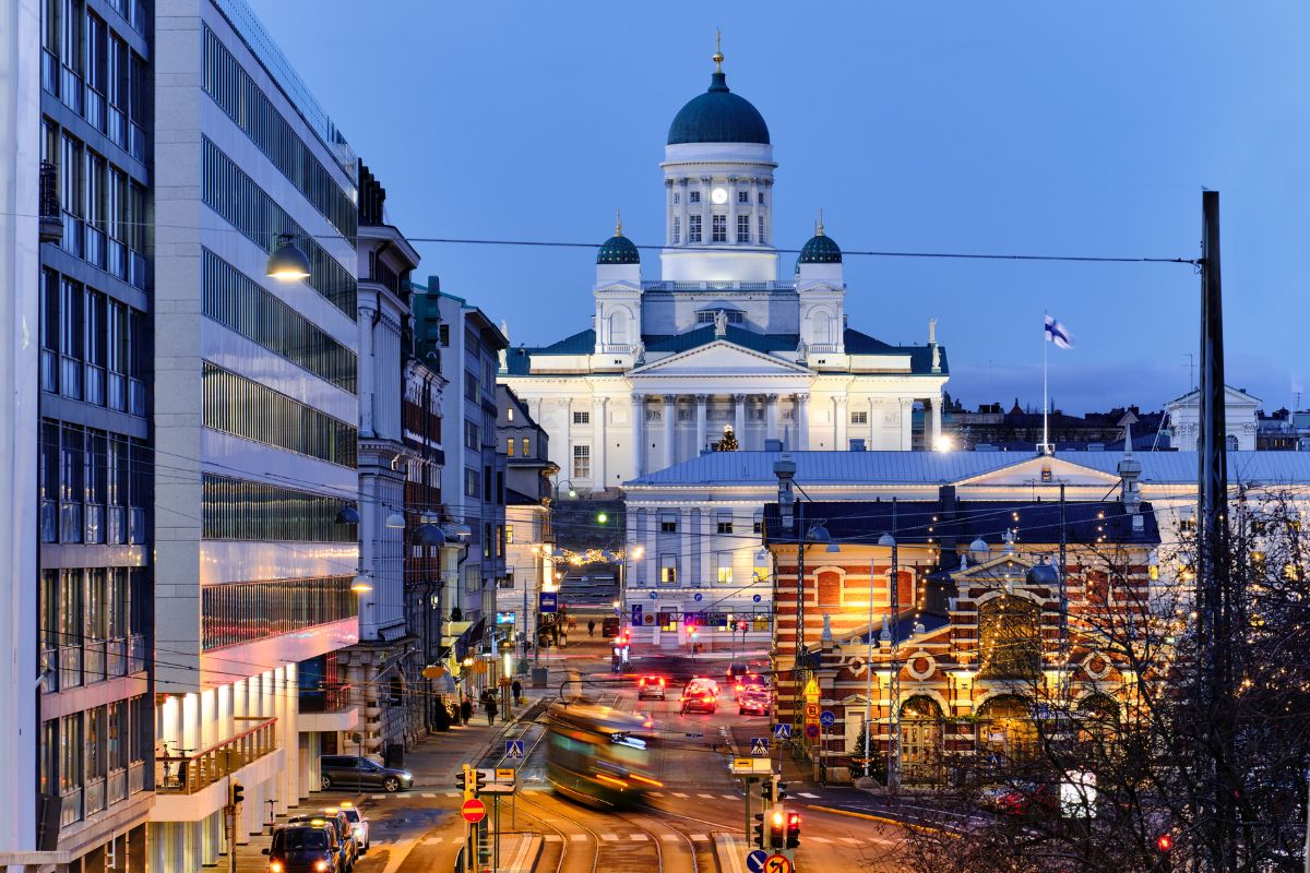 Helsingfors saluhall och domkyrka i skymning med trafik och ljus i förgrunden.