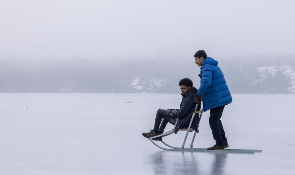 Two boys on a kick sled on ice