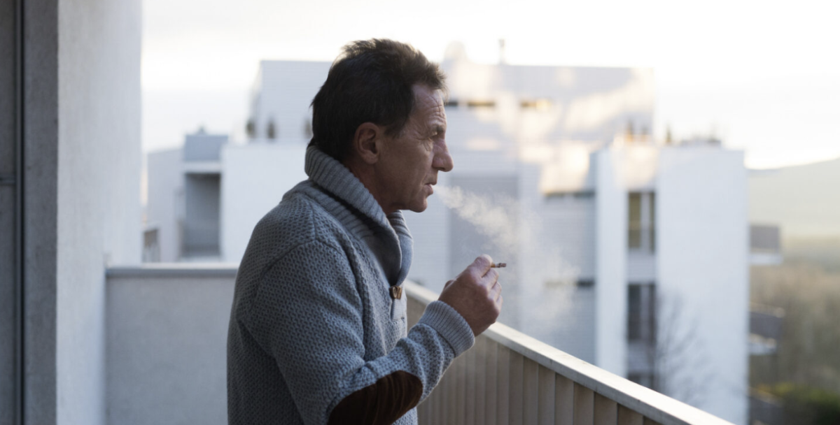 Smoking man standing on a balcony.