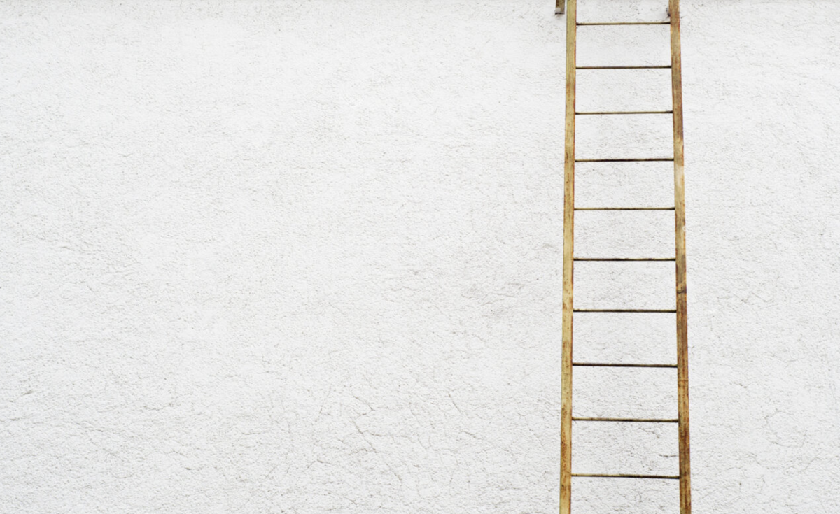 A ladder leaning against a white wall.